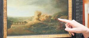 Das Rembrandt-Gemälde Landschaft mit Bogenbrücke - mit einer weiblichen Hand, die auf das Bild weist.