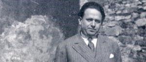 Kurt Tucholsky mit Stock vor einer Mauer stehend.