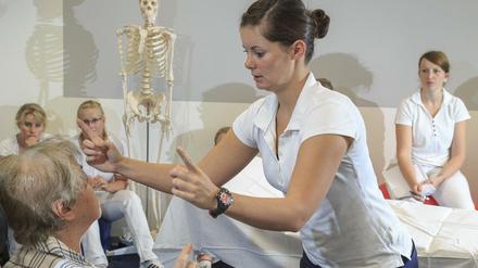 Physiotherapiestudierende üben in einer Hochschule an einer Patientin, die sich als Freiwillige zur Verfügung gestellt hat.