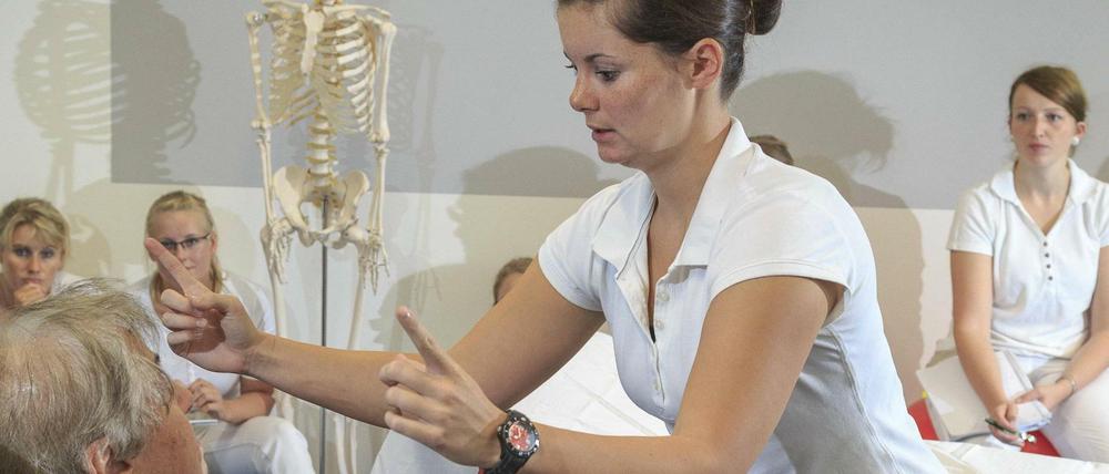 Physiotherapiestudierende üben in einer Hochschule an einer Patientin, die sich als Freiwillige zur Verfügung gestellt hat.