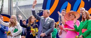 König Willem-Alexander steht mit seiner Ehefrau Maxima und den gemeinsamen Töchtern auf der Bühne und winkt.