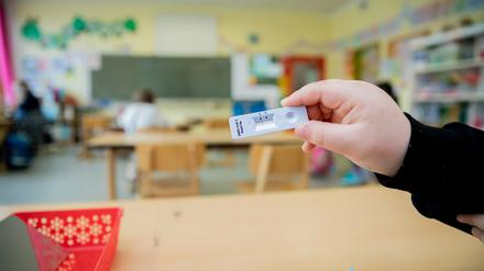 Schüler hält an der Grundschule in der Köllnischen Heide in Neukölln seinen negativen Test in die Kamera.