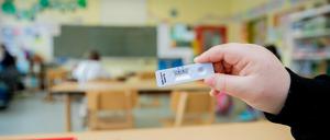 Schüler hält an der Grundschule in der Köllnischen Heide in Neukölln seinen negativen Test in die Kamera.