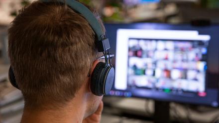 Ein Mann sitzt an seinem Computer vor einer laufenden Videokonferenz.