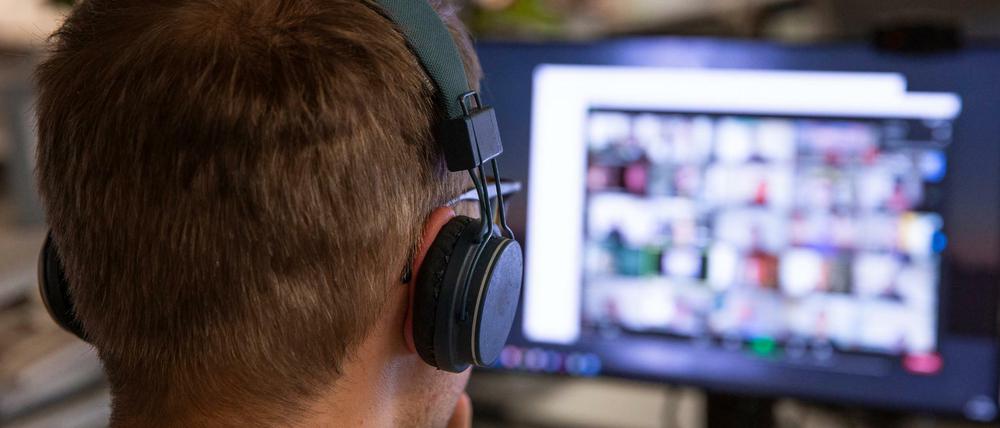 Ein Mann sitzt an seinem Computer vor einer laufenden Videokonferenz.