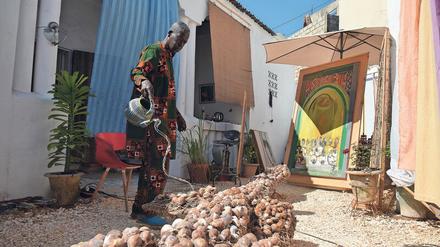 Bewässerung eines Kunstwerks. El Hadji Sy begießt im Hof seines Atelierhauses ein aus Muscheln gebildetes Krokodil, das im Juni auf der Dakar-Biennale zu sehen sein wird.