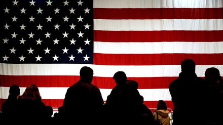Besucher stehen auf der Air Base in Ramstein vor einer US-Flagge im Gegenlicht. 