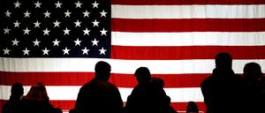 Besucher stehen auf der Air Base in Ramstein vor einer US-Flagge im Gegenlicht. 