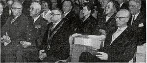 Auf einem historischen Zeitungsfoto sitzen festlich gekleidete Männer und Frauen bei einer Feierstunde in einem Hörsaal.
