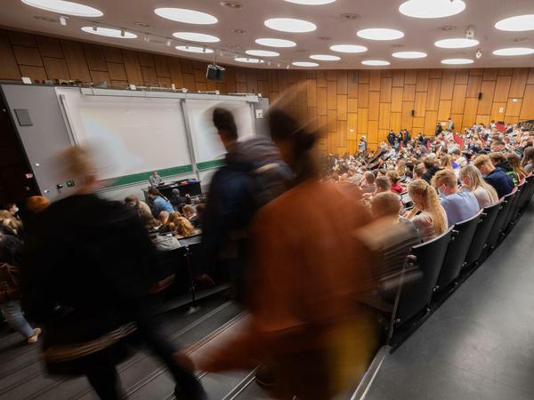 Ein voller Hörsaal, auf der Treppe laufen Studierende auf der Suche nach einem freien Platz.