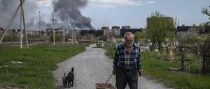 Ein Mann in Mariupol, im Hintergrund Rauchwolken über dem umkämpften Stahlwerk