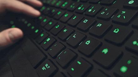 Ein Mann tippt an einer beleuchteten Tastatur.