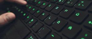 Ein Mann tippt an einer beleuchteten Tastatur.