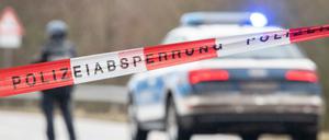 Polizeibeamte stehen an einer Absperrung an der Kreisstraße 22, rund einen Kilometer von dem Tatort entfernt.