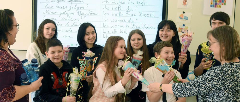 Eine Lehrerin begrüßt ukranische Schülerinnen mit kleinen Schultüten.