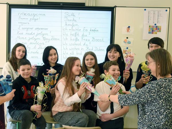 Eine Lehrerin begrüßt ukranische Schülerinnen mit kleinen Schultüten.
