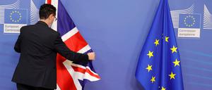 Ein Mitglied des Protokolls richtet die EU- und Fahne Großbritanniens vor einem Treffen im EU-Hauptquartier. 