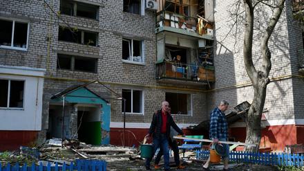 Männer gehen an einem Wohnhaus vorbei, das durch nächtlichen Beschuss zerstört wurde. 