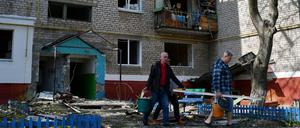 Männer gehen an einem Wohnhaus vorbei, das durch nächtlichen Beschuss zerstört wurde. 