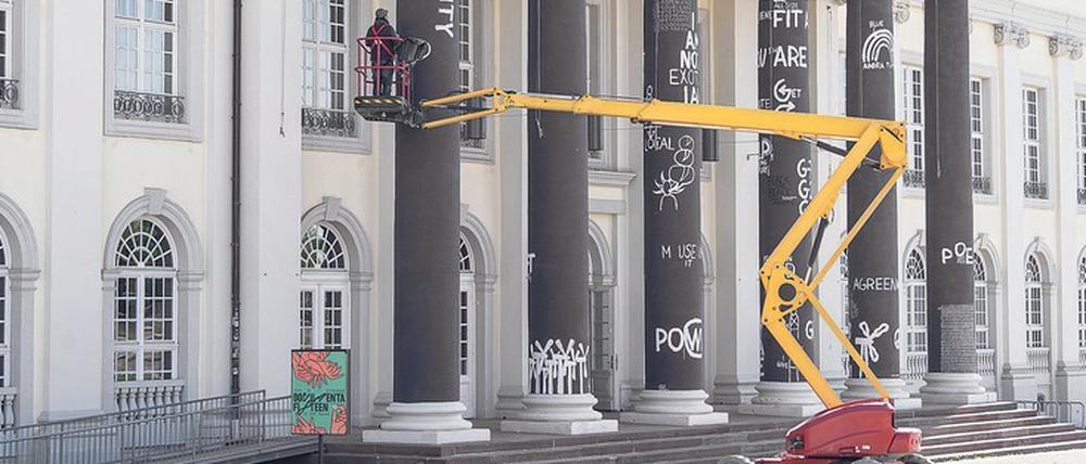 Der Künstler Dan Perjovschi malt im Rahmen der Documenta 15 Slogans auf die Säulen vor dem Fridericianum.