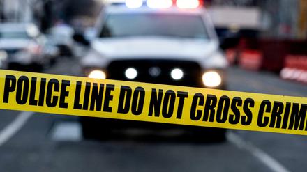 Ein Polizeiauto vor einer Absperrung.