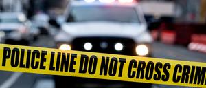 Ein Polizeiauto vor einer Absperrung.