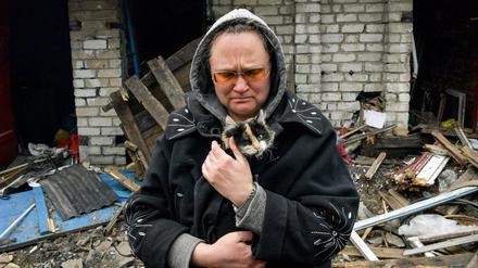 Eine Frau mit ihrer Katze in einem zerstörten Dorf in der Region Luhansk