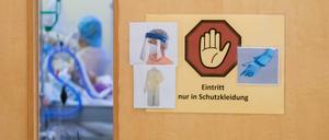 Ein Warnschild zum Tragen von Schutzkleidung hängt auf der Intensivstation des Gemeinschaftskrankenhauses Havelhöhe an der Tür eines Covid-19-Patientenzimmers.