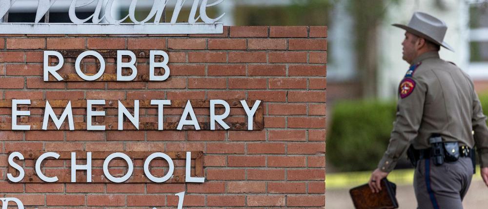 Ein Polizist geht nach einem Amoklauf an der Grundschule Robb Elementary School an einem Schriftzug der Schule vorbei.
