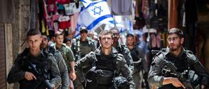 Polizisten sichern Israelis, die mit Flaggen durch die Altstadt Jerusalems gehen.
