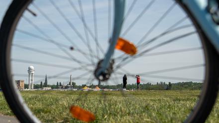 Menschen genießen das sonnige Wetter auf dem Tempelhofer Feld vor der Kulisse des alten Flughafens. 