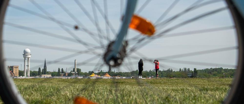Menschen genießen das sonnige Wetter auf dem Tempelhofer Feld vor der Kulisse des alten Flughafens. 