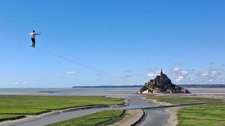 Der Hochseilkünstler Nathan Paulin balanciert auf die Felseninsel Le Mont Saint-Michel zu.