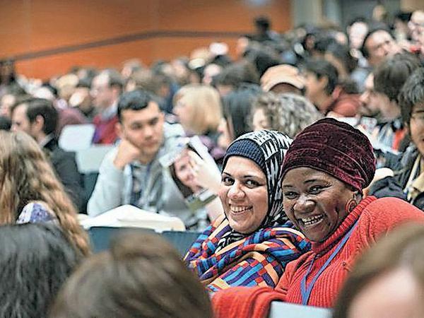 Zwei DAAD-Stipendiatinnen aus dem globalen Süden sitzen lächelnd in einem Hörsaal.