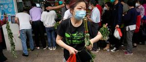 Einwohner stehen Schlange, um auf einem Markt Gemüse zu kaufen. 