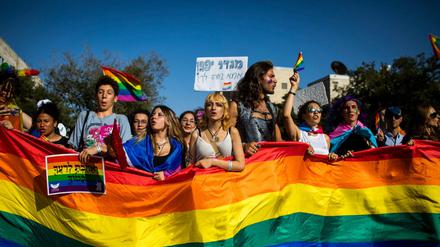 Menschen marschieren mit Regenbogenfahnen und Schildern während der jährlichen Gay-Pride-Parade in Jerusalem.