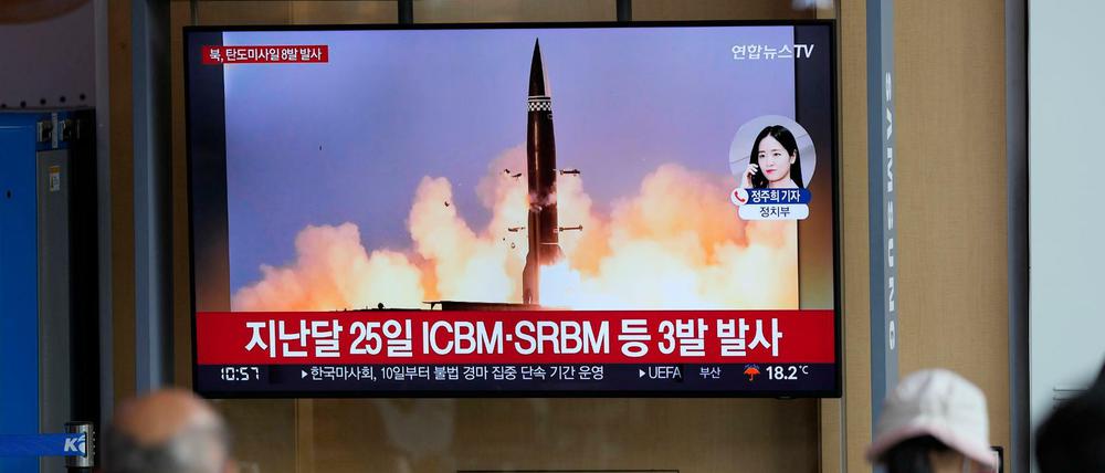 Menschen sehen einen Fernsehbildschirm, auf dem eine Nachrichtensendung über den nordkoreanischen Raketenstart gezeigt wird.