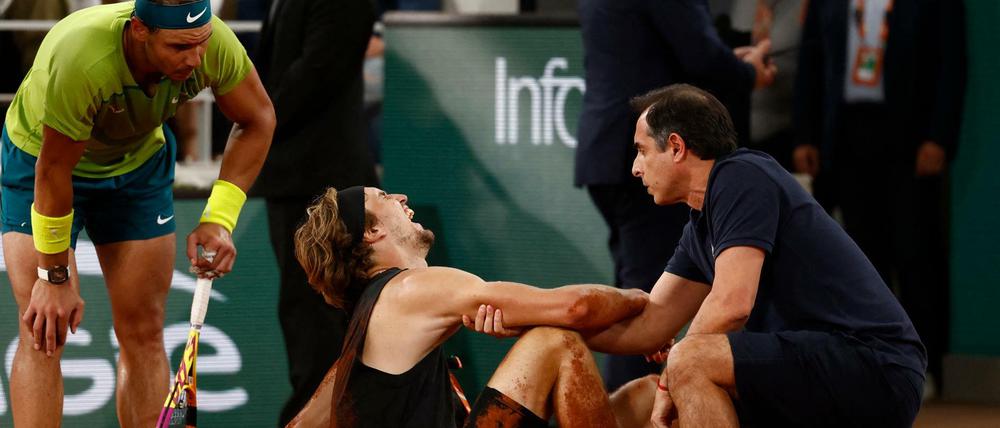 Alexander Zverev kann aus eigener Kraft nicht mehr aufstehen, Rafael Nadal bietet seine Hilfe an.