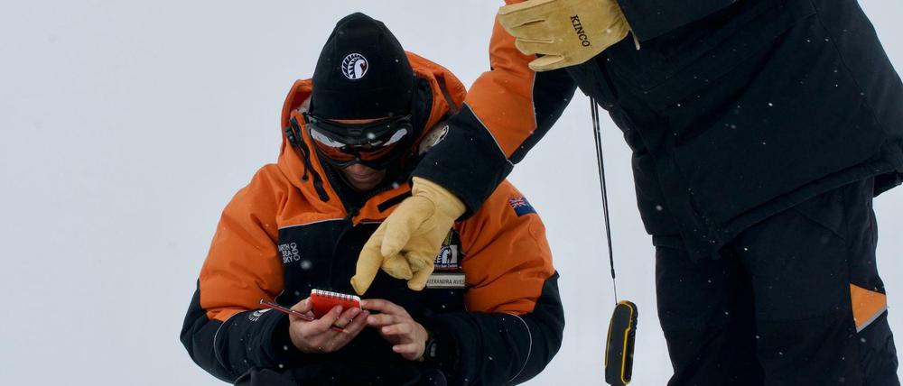 Alex Aves (l.) von der Canterbury University notiert Daten während der Probennahme von Schnee in der Antarktis. 