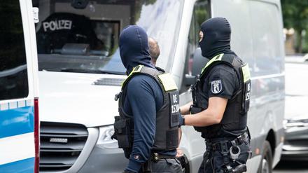 Vermummte Polizisten führen bei der Razzia in der Bülowstraße einen Mann ab.