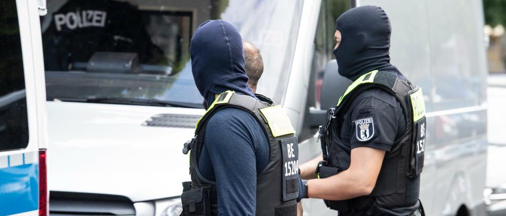 Vermummte Polizisten führen bei der Razzia in der Bülowstraße einen Mann ab.
