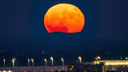 Der Vollmond geht am Abend über dem Flughafen München im Hallbergmoos auf.