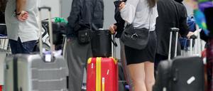Fluggäste warten am Düsseldorfer Flughafen vor einem Check-In-Schalter auf ihre Abfertigung (Archivfoto).
