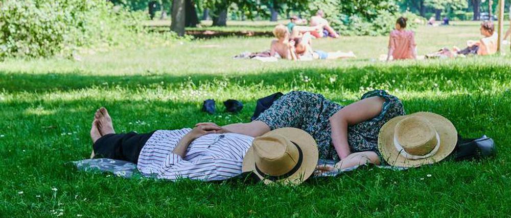Hitze in Berlin: Zwei Menschen liegen mit Strohhut über dem Gesicht im Tiergarten.