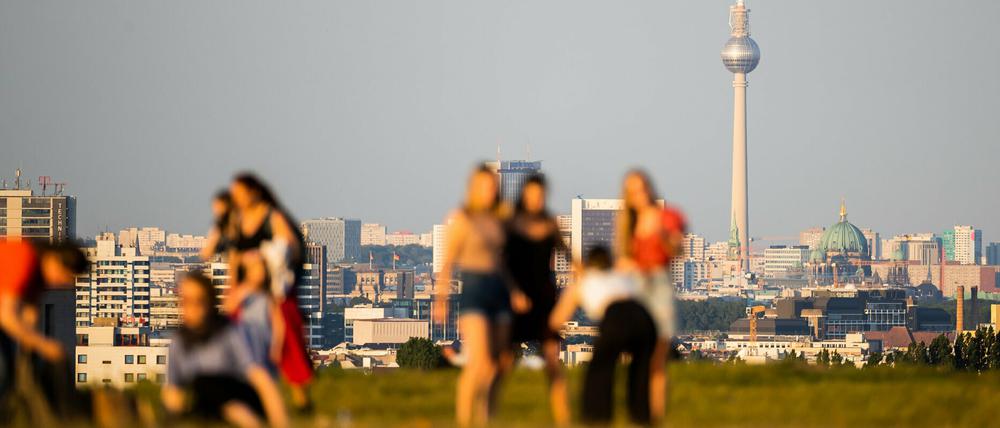 Menschen genießen vor dem Berliner Fernsehturm einen sonnigen Abend auf dem Drachenberg.