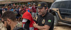 Bundespolizisten eskortieren einen Verdächtigen an Bord eines Bootes zu dem Ort, an dem die Suchaktion stattfindet.