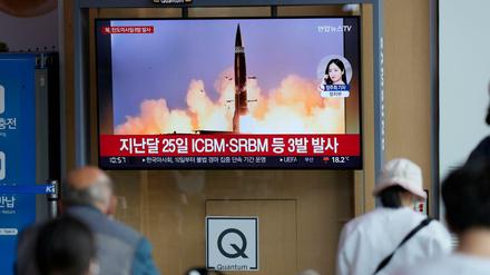 Menschen sehen einen Fernsehbildschirm, auf dem eine Nachrichtensendung über den nordkoreanischen Raketenstart gezeigt wird.