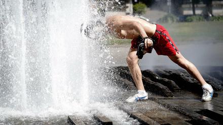 Ein Passant erfrischt sich im Brunnen im Lustgarten bei hohen Temperaturen.