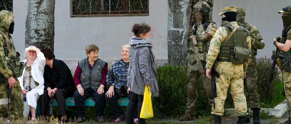 Ältere Anwohner sprechen mit einer Gruppe russischer Soldaten in Cherson am 20. Mai 2022.