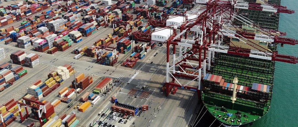 In einem Hafen der ostchinesischen Provinz Shandong wird ein Schiff mit Containern beladen.